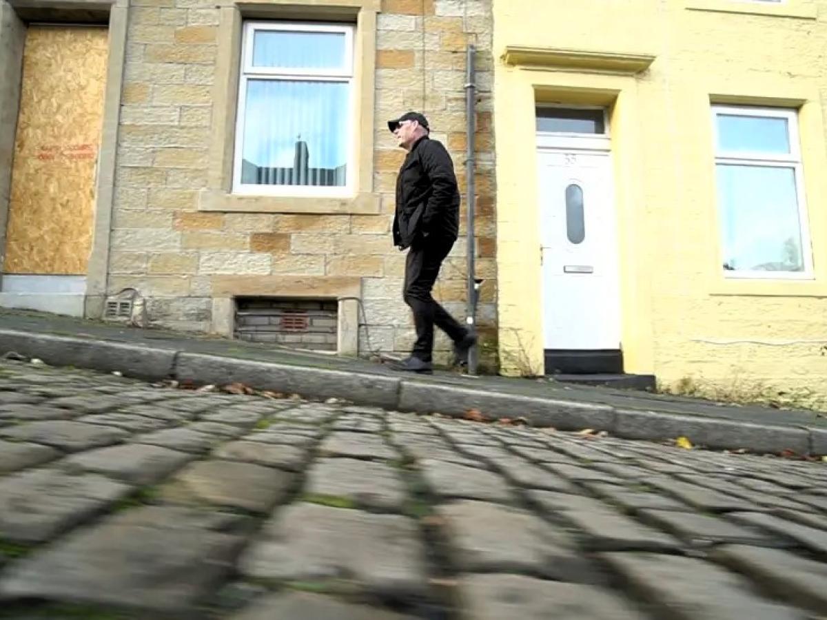 A man walks up a cobble street.