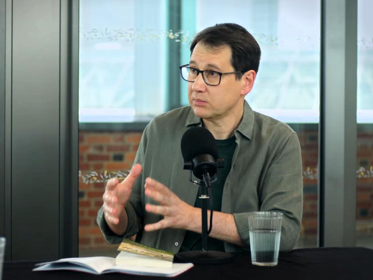 A podcast guest gestures with their hands.