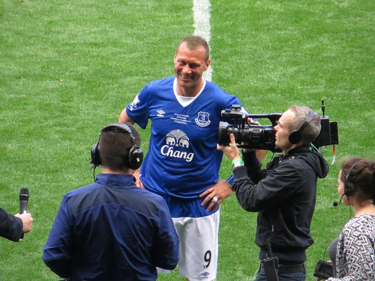 A footballer is interviewed on the side line.