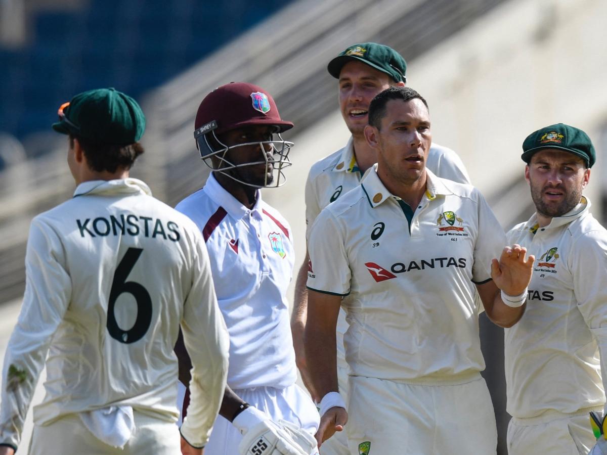 A cricket batsman surrounded by opposition players leaves the crease.