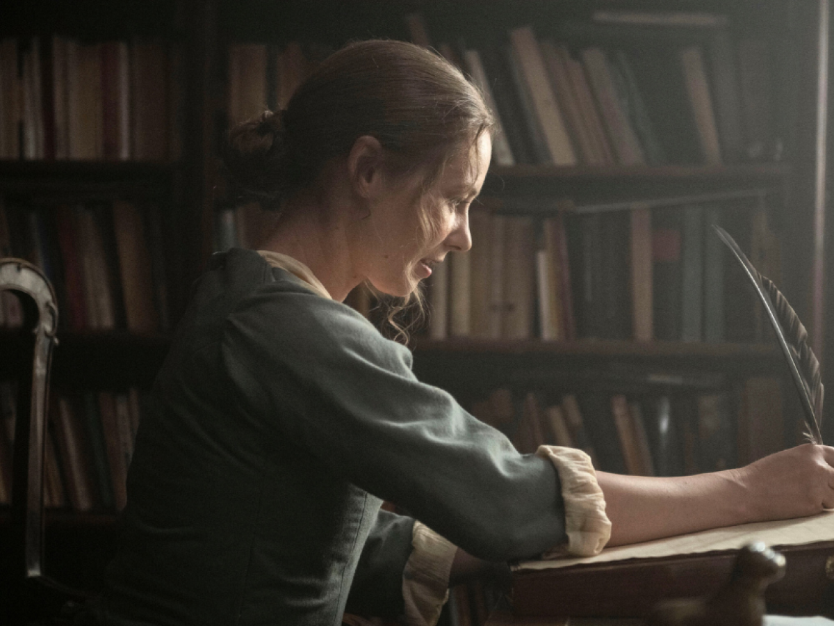 A regency woman writes with a quill