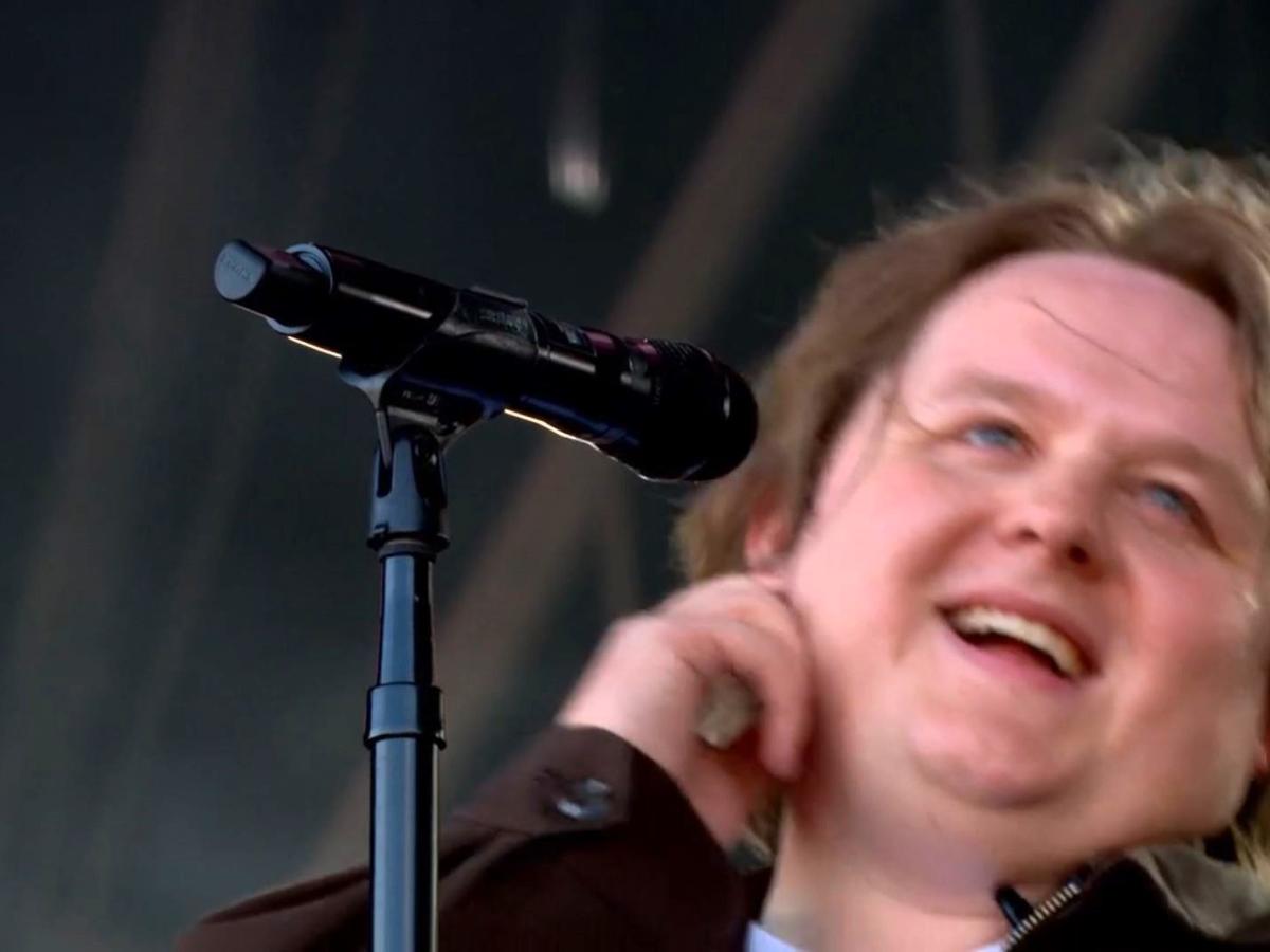 A singer leans back from the mic smiling