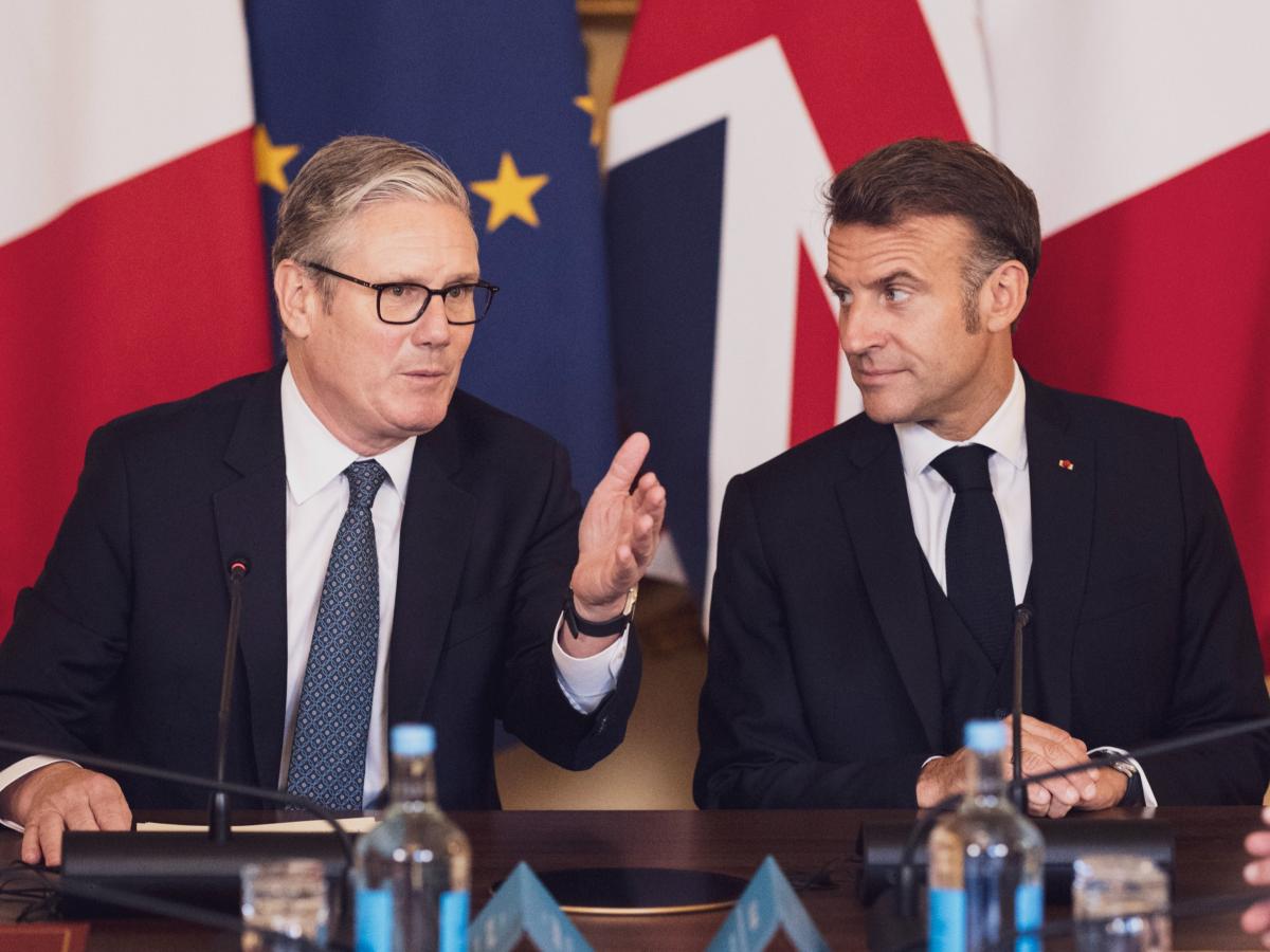 Keir Starmer and Emmanuel Macron in front of flags.