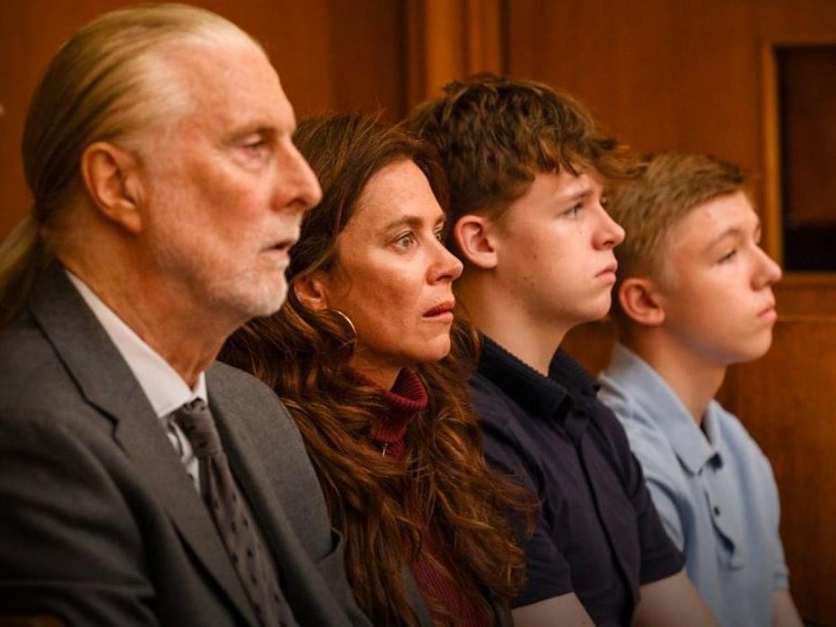 A family sit together watching a trial in a court.
