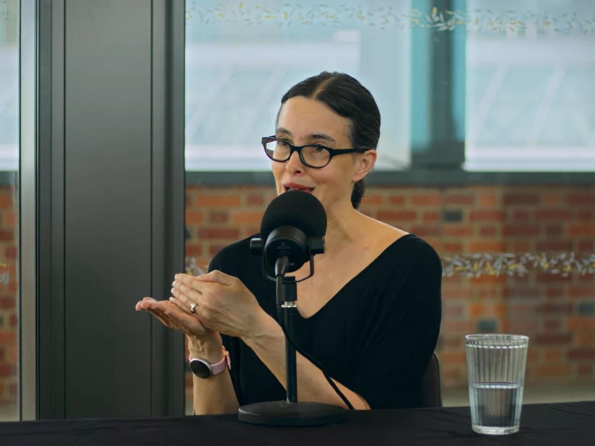 a woman speaks and gestures while recording a podcast