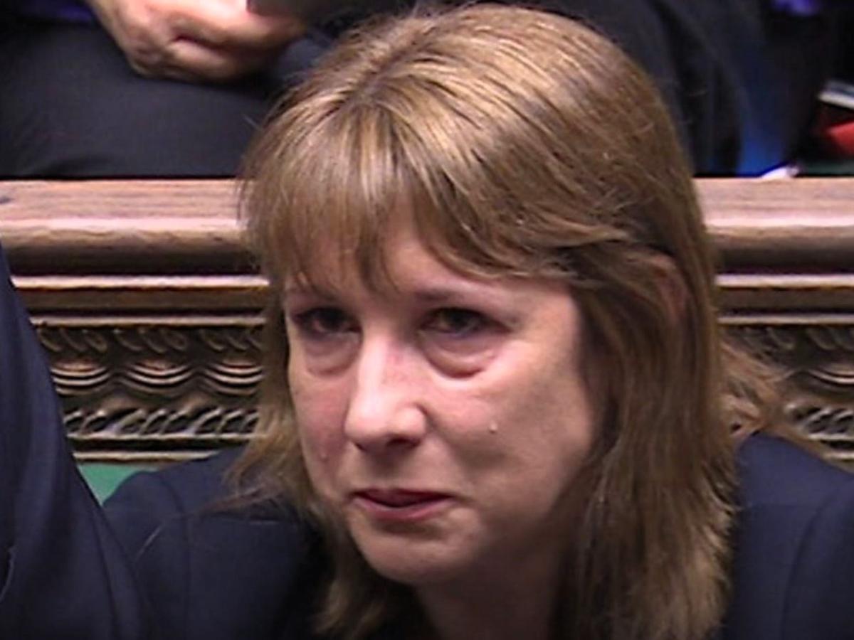 A woman sits and holds back a tear.