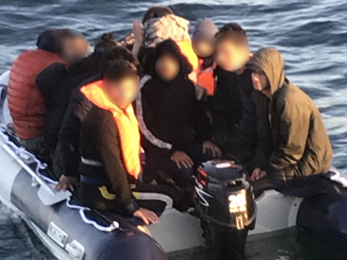 A people sumggler steers an overcrowded small boat.