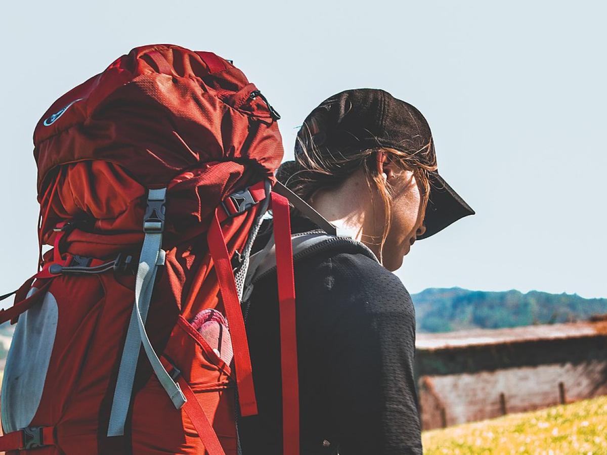 A pilgrim with a red backpack heads off.