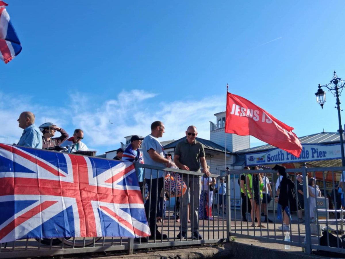 A Union Jack is draped over a railing, next to a red flag saying Jesus.
