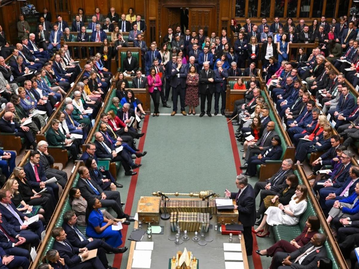 MPs sit and stand in a crowded parliament.