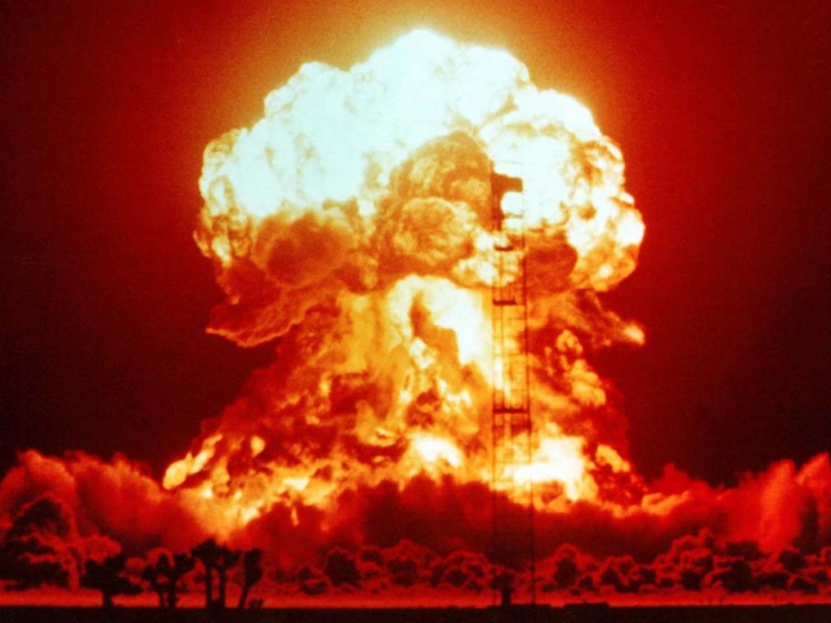 A nuclear explosion glows red and orange against the night sky.