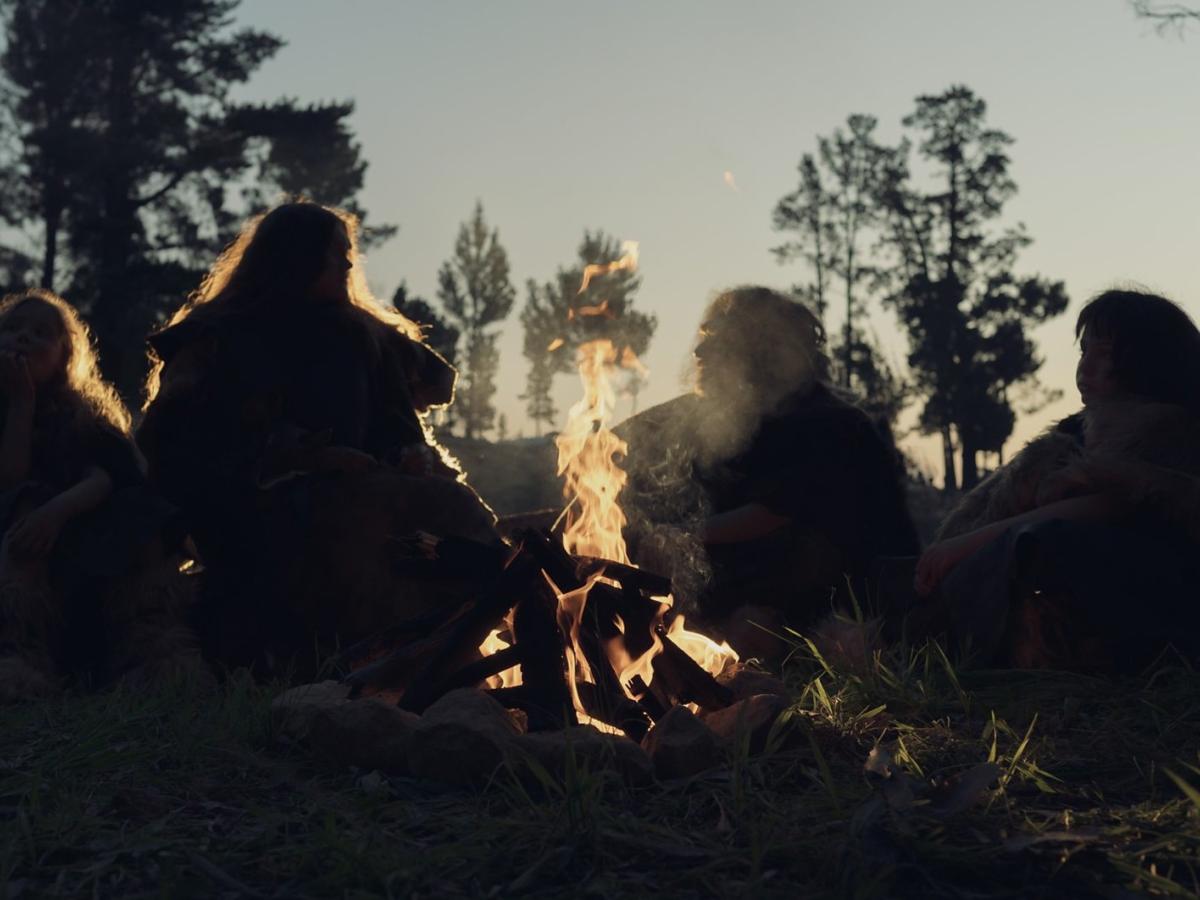 A re-enactment of an ancient 'caveman' family sitting around a camp fire.