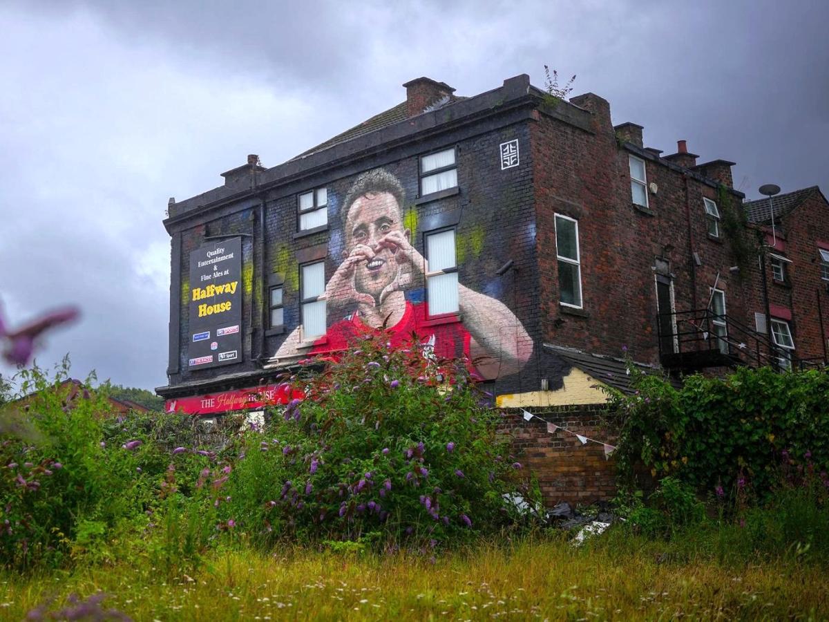 A mural on a side of a pub shows a footballer making a heart sign.