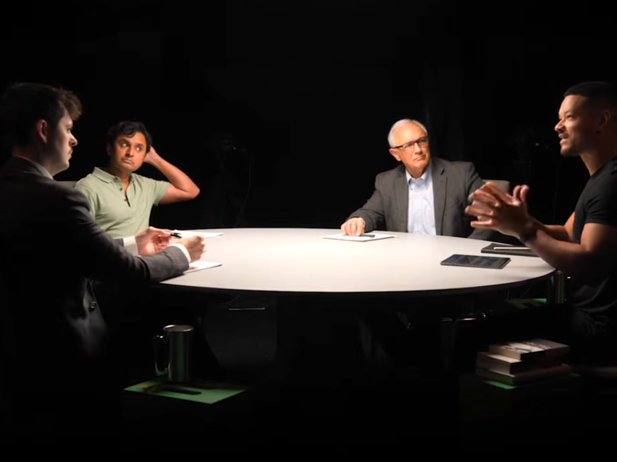 A spotlit round table with podcast guests around it.