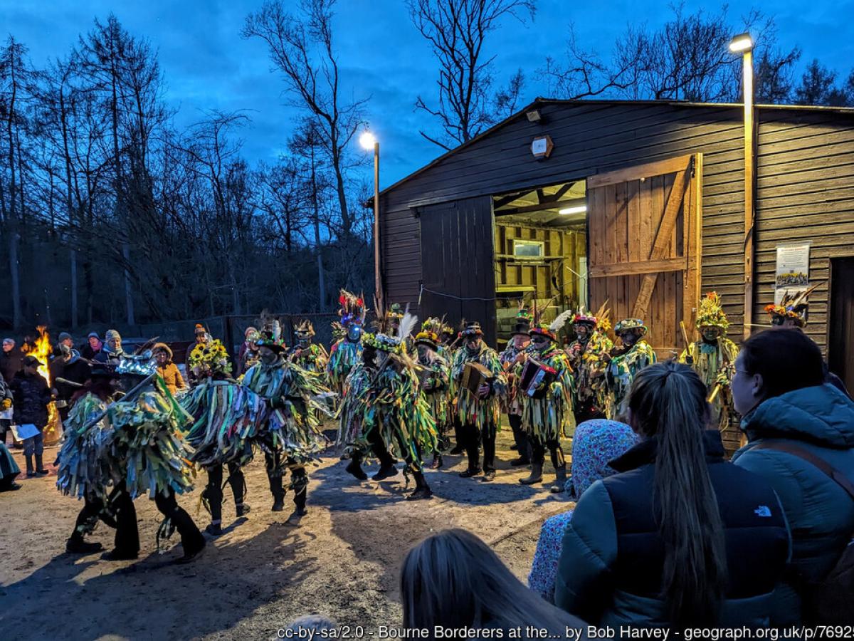 Wassailers emerge from a shed beside a wood