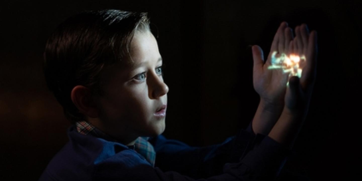 A cinematic view of a child holding an image that lights up their face.