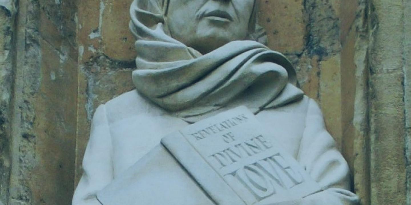 A statue of a Medieval women wearing a headscarf, and holding a book inscribed: revelation of divine love.o