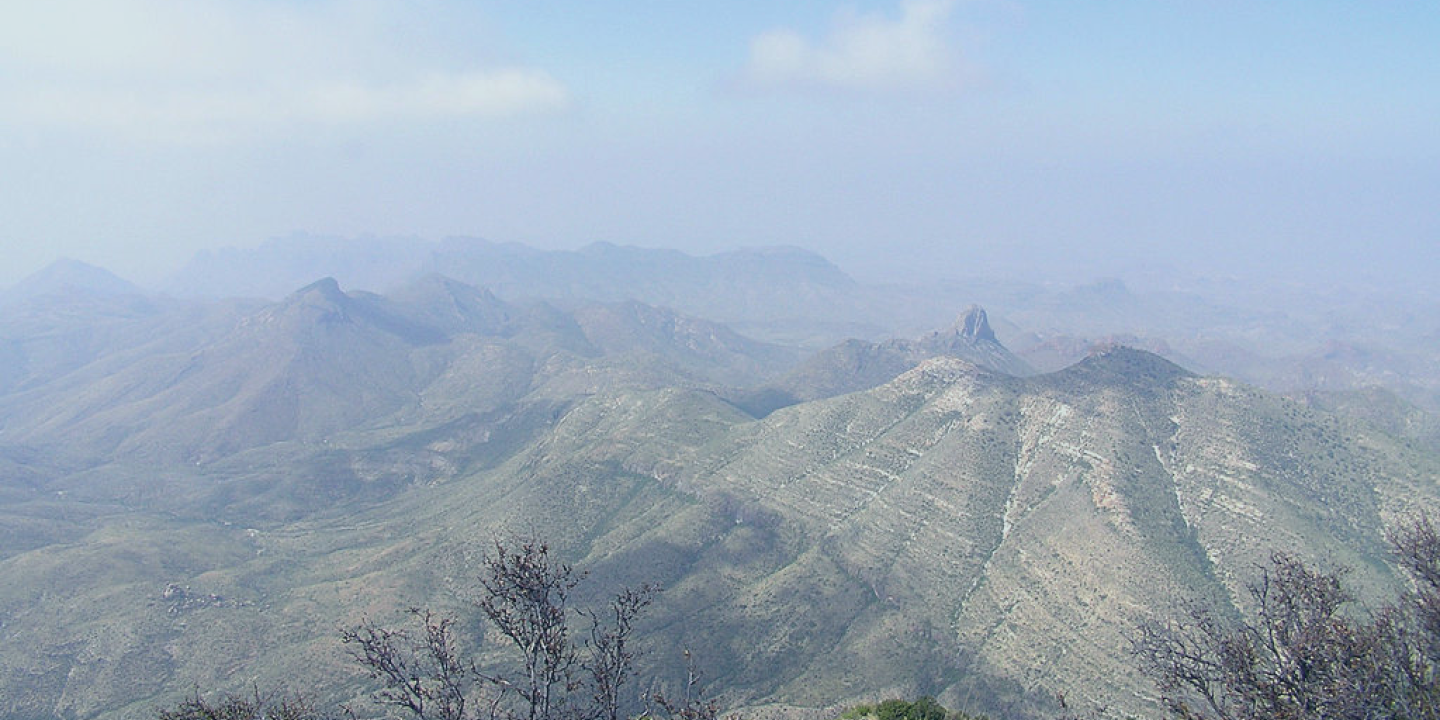 A view of a lightly misted valley to mountains in a desert area.