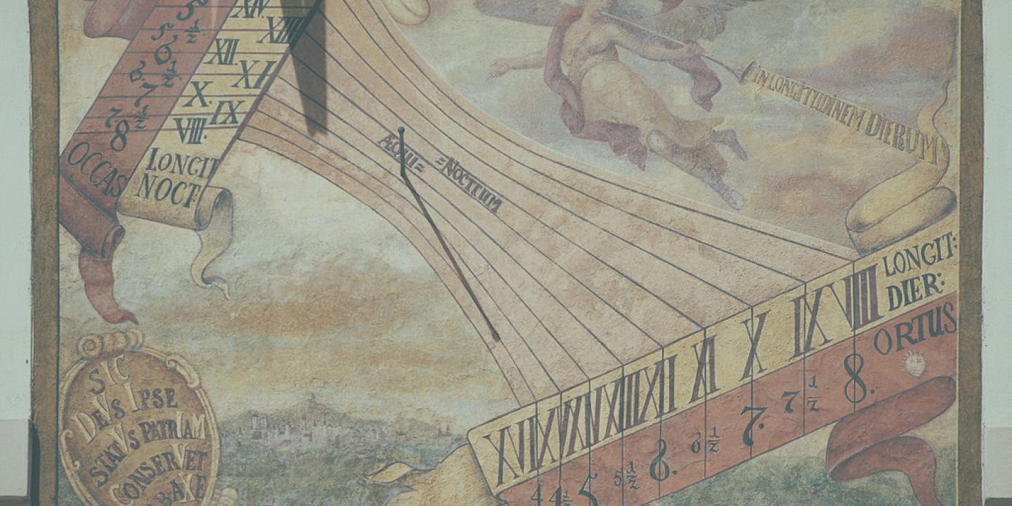 A sundial on a wall casts a small shadow on a painted list of numbers and symbols