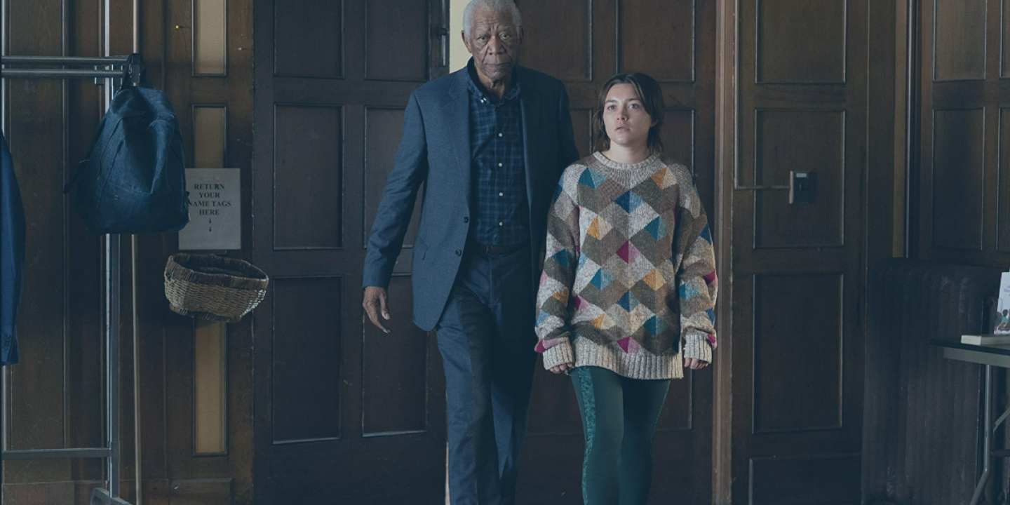 An old man accompanies a young woman into a wood-panelled hall, both look aprehensive.