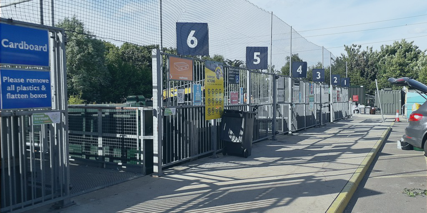 A recyling centre with numbered bays and high netting to catch wind-blown waste.