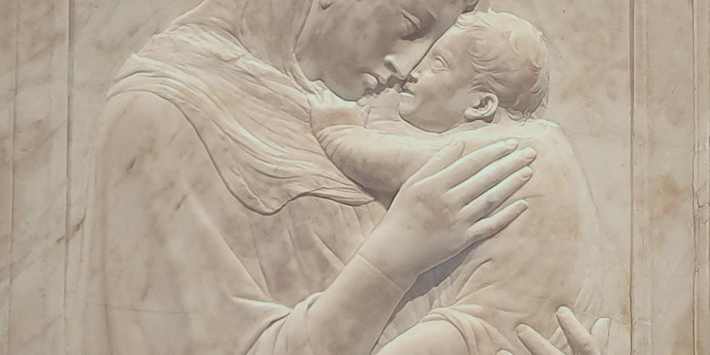 A relief sculpture shows the Madonna hold the infant Christ close to her face.