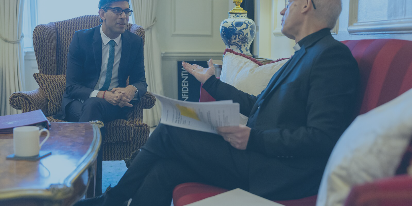 Prime minister Rishi Sunak leans forward out a lounge chair while the Archbishop of Canterbury talks and gestures while sitting on a sofa.