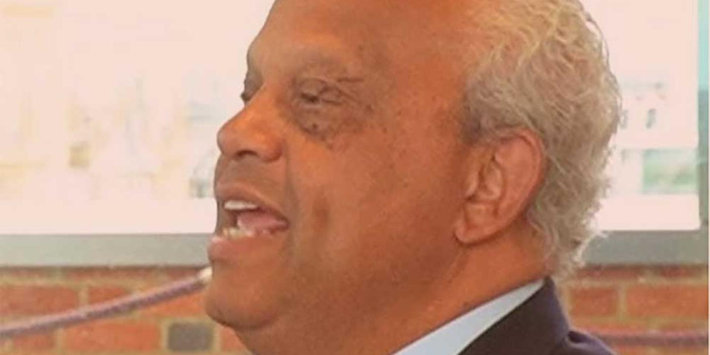A man in conversation laughs and throws his head back