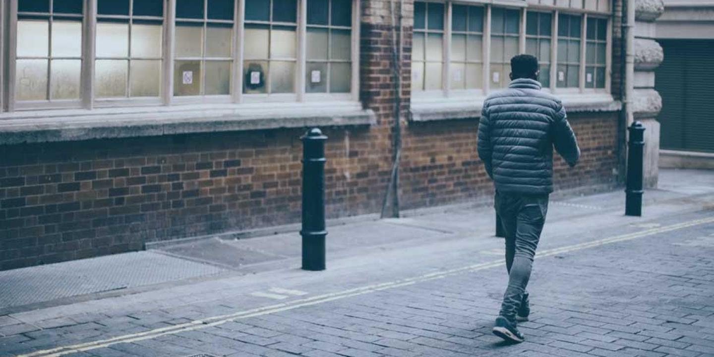 A man walks away down a drab street