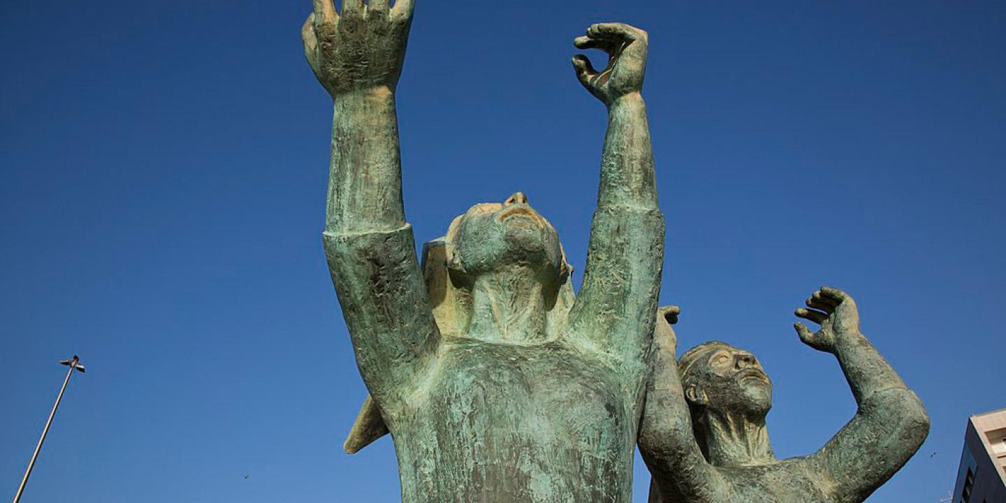 A sculpture shows mourning women raising hands and fists to the sky.