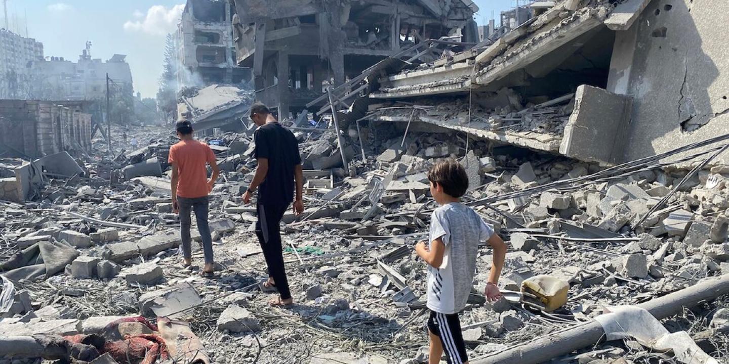 People walk across the rubble beside a recently bombed building.