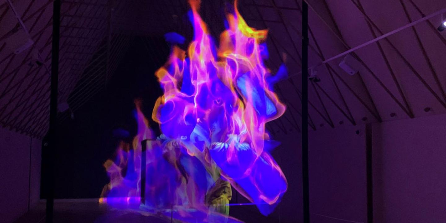A art installaton showing purple and pink flame-like shapes moving in a darkened room