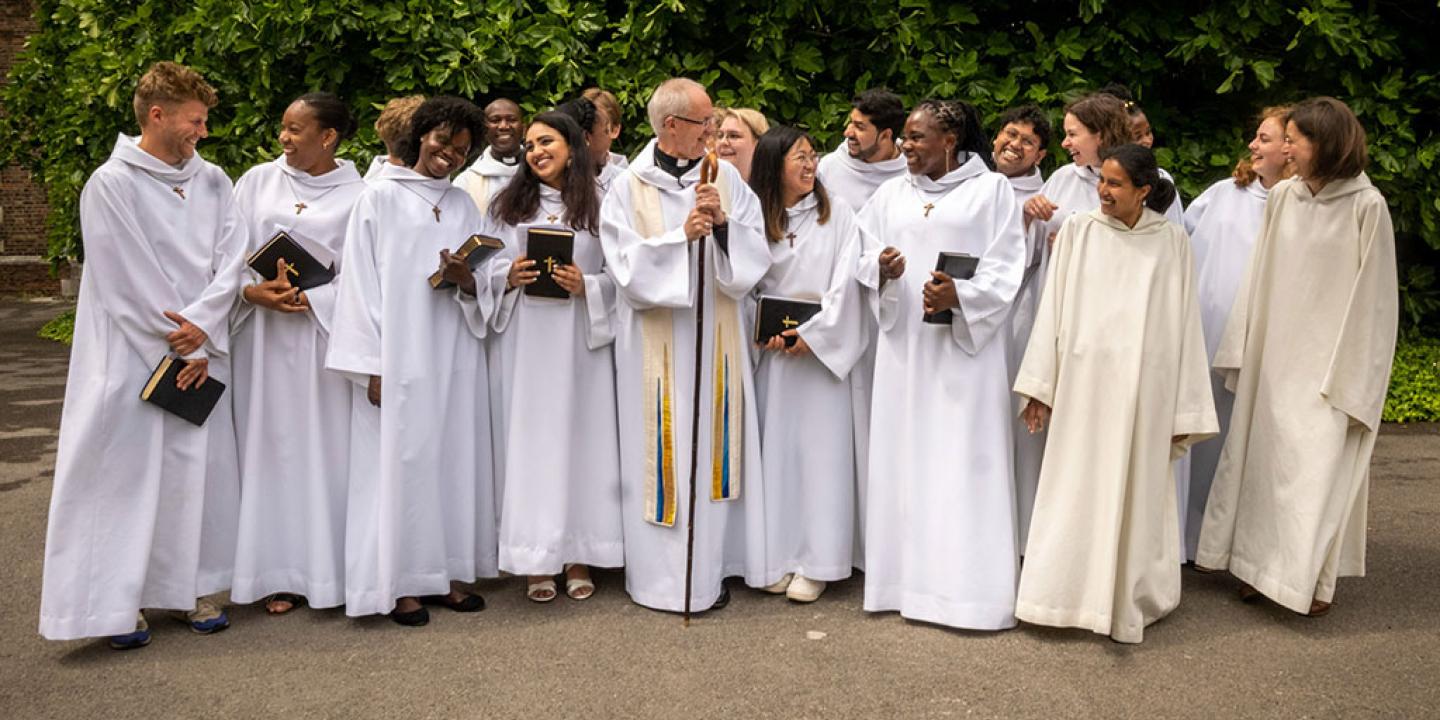 A group of young people wearing white habits stand and laugh with each other.