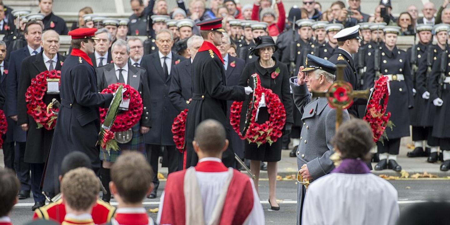 Princes and army officers walk away from a war memorial while others look on.