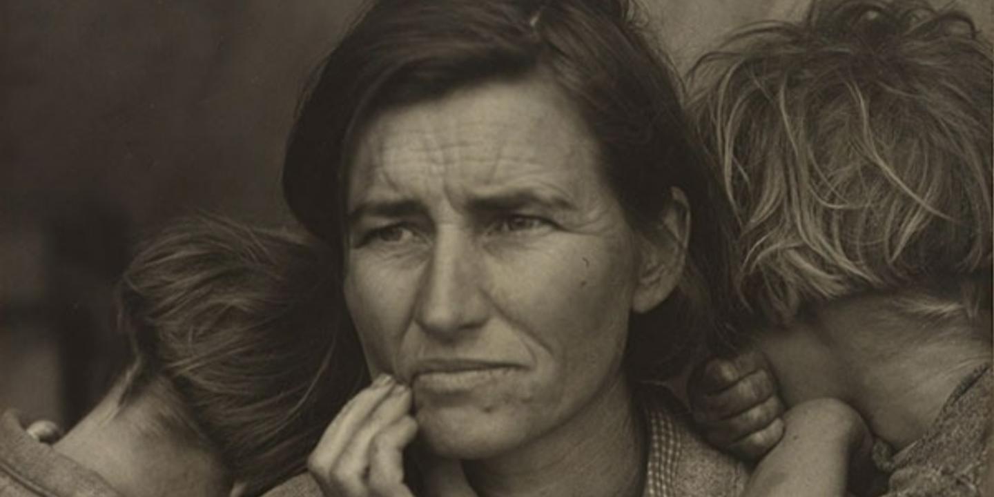 A black and white close up of a mothers cradling her jaw in worry as children cuddle into her.