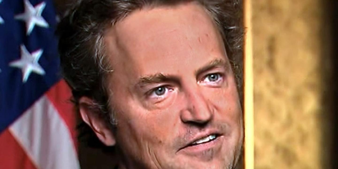 Actor Matthew Perry looks formally away, with a US flag in the background