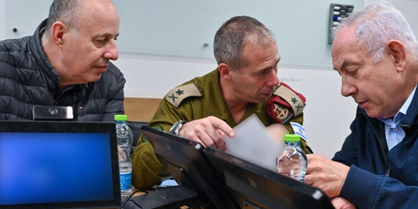 Three men huddle around a laptop and talk animatedly.