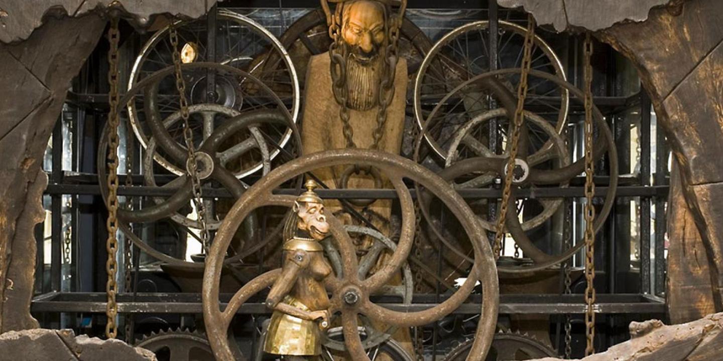 A close-up of a complex clock mechanism featuring small statues within it.
