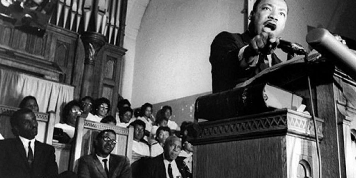 Martin Luther King reaches from the pulpit of a church while he preaches.