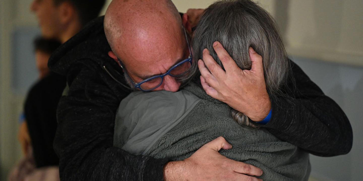 A re-united couple hug each other deeply.