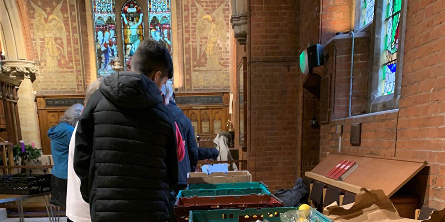 clients of a charity queue beside a table of suppliers in a church