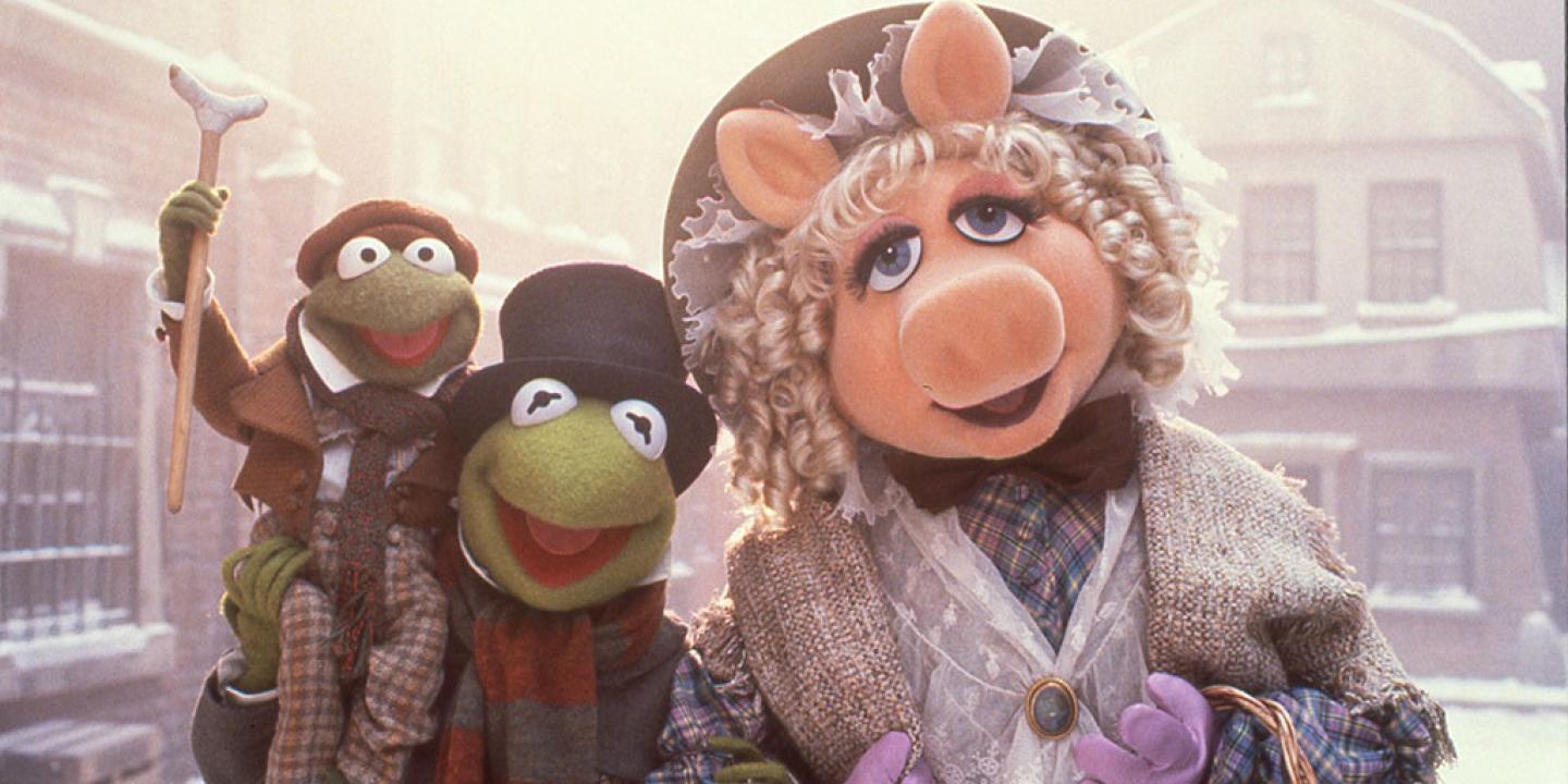 Muppet characters dressed as Dickensian characters stand in a snowy street.