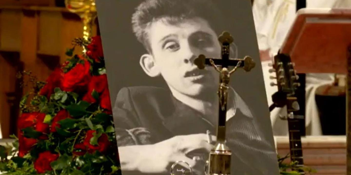 Upon his draped coffin, a picture of Shane MacGowan and a crucifix sit