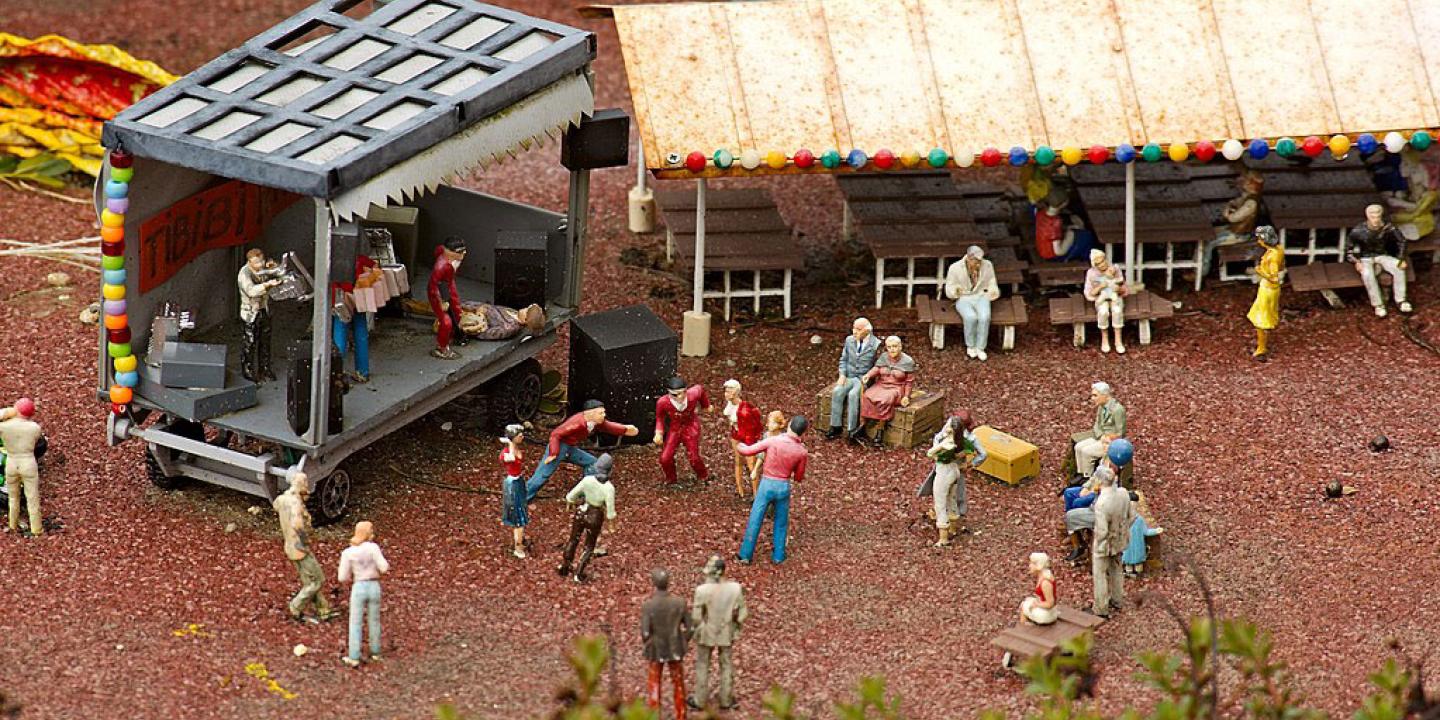 A miniature tableau depicts a band performing at a concert as people dance and others watch from a marque.