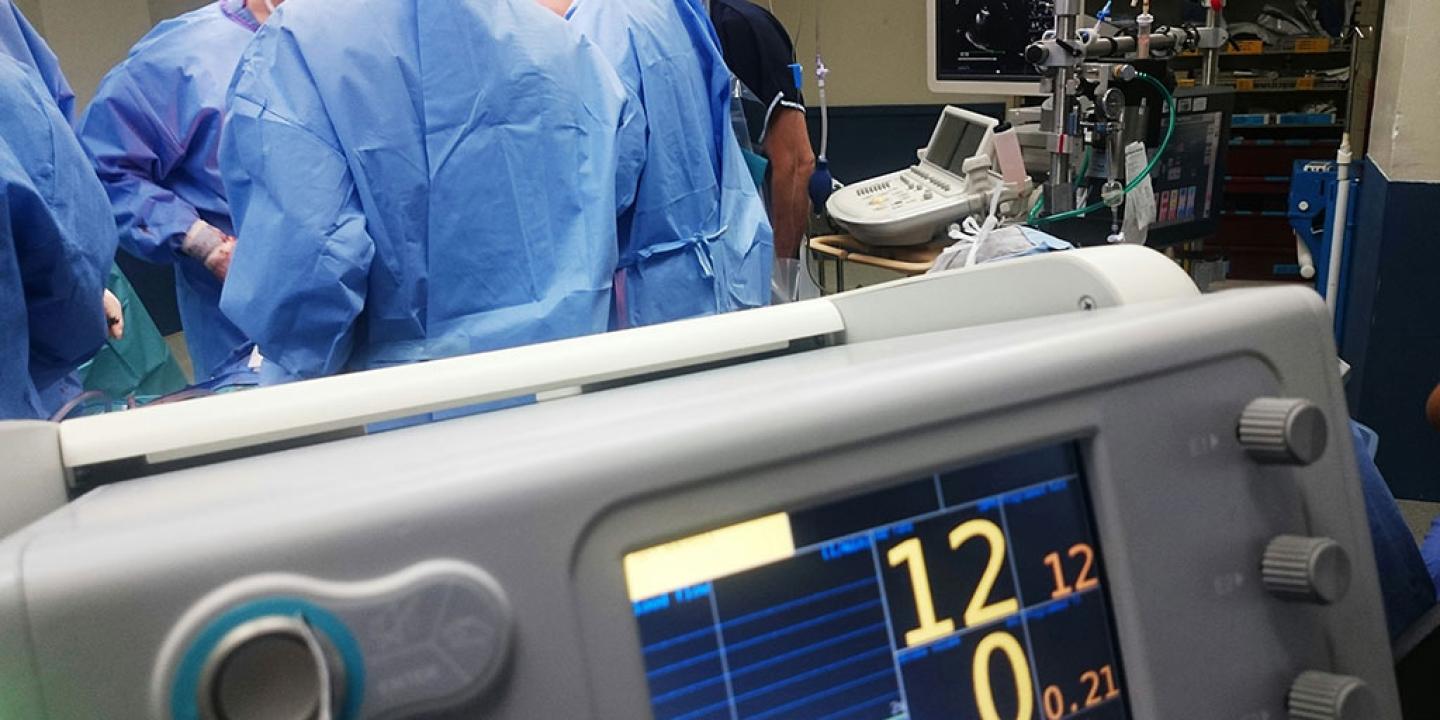 While surgeons operate in the background a digital display shows numbers in the foreground