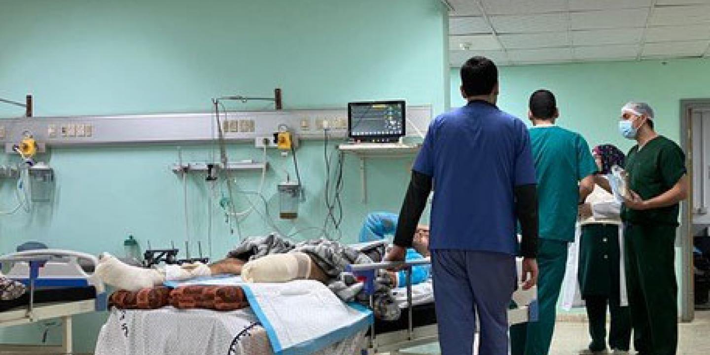 Medical staff stand beside a bed in which a man lies with an amputated leg.