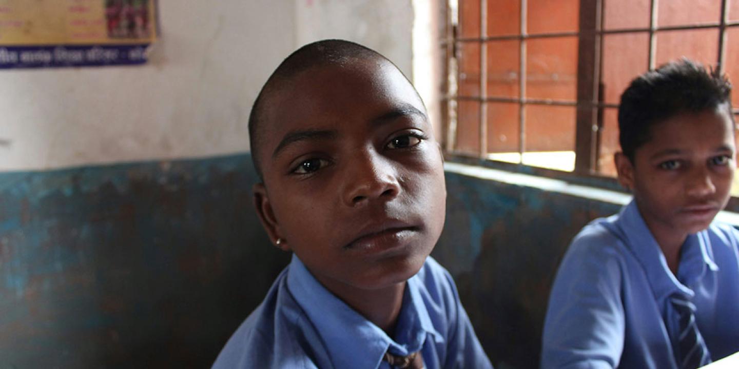 A pupil in a classroom looks around and into the camera.