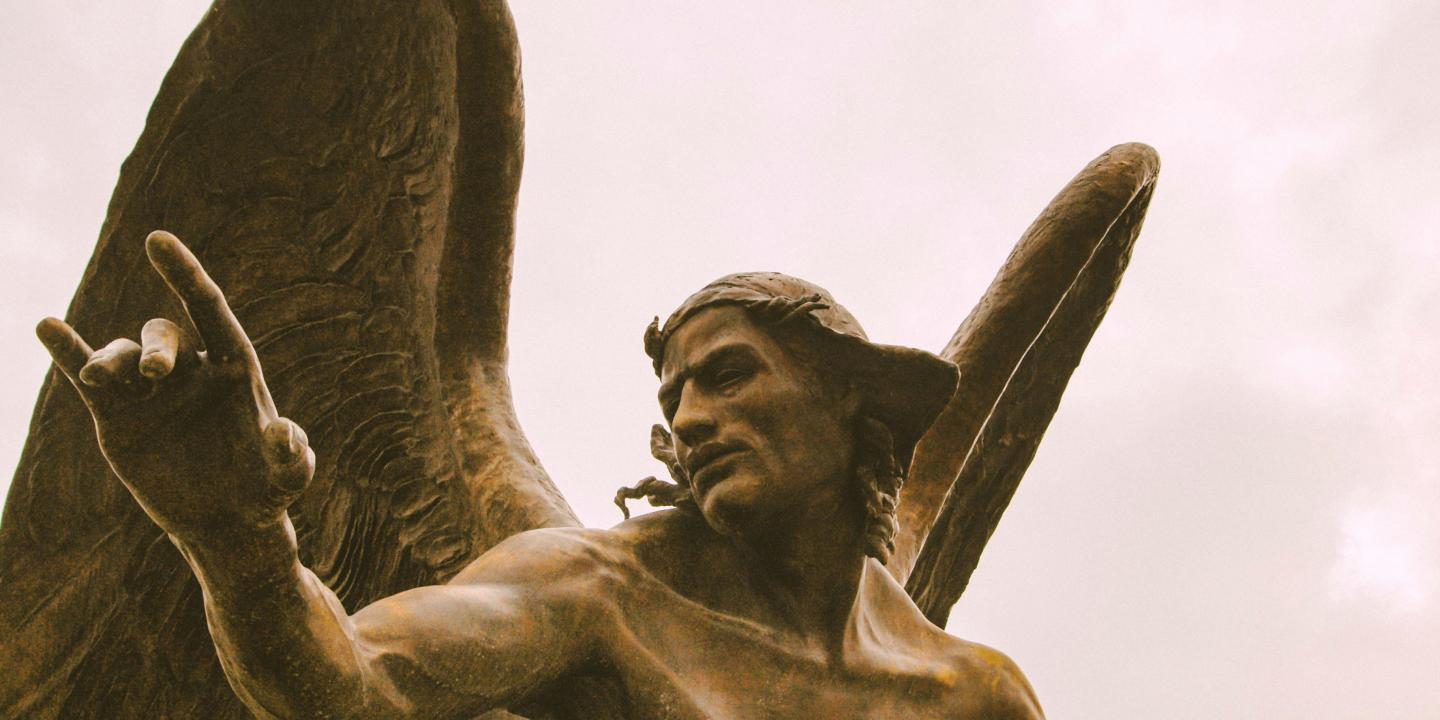 A statue of an angel crouching and gesturing with one hand.