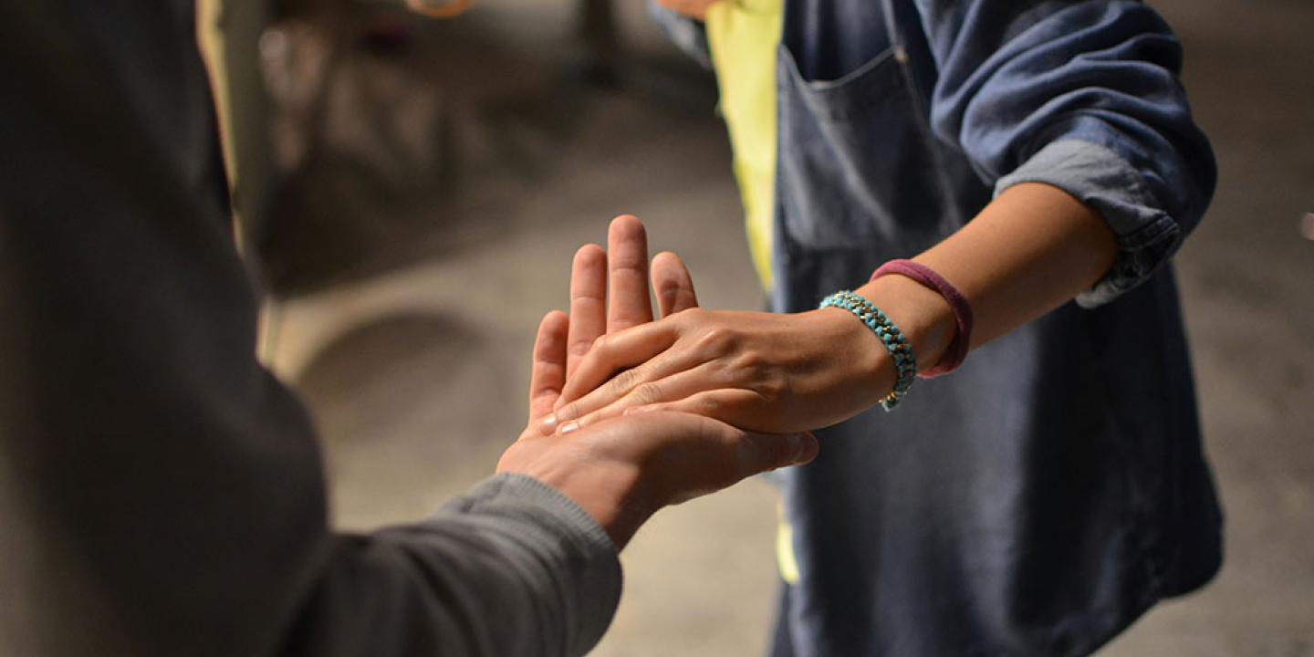 A hand held out is gentle grasped by a turning person.