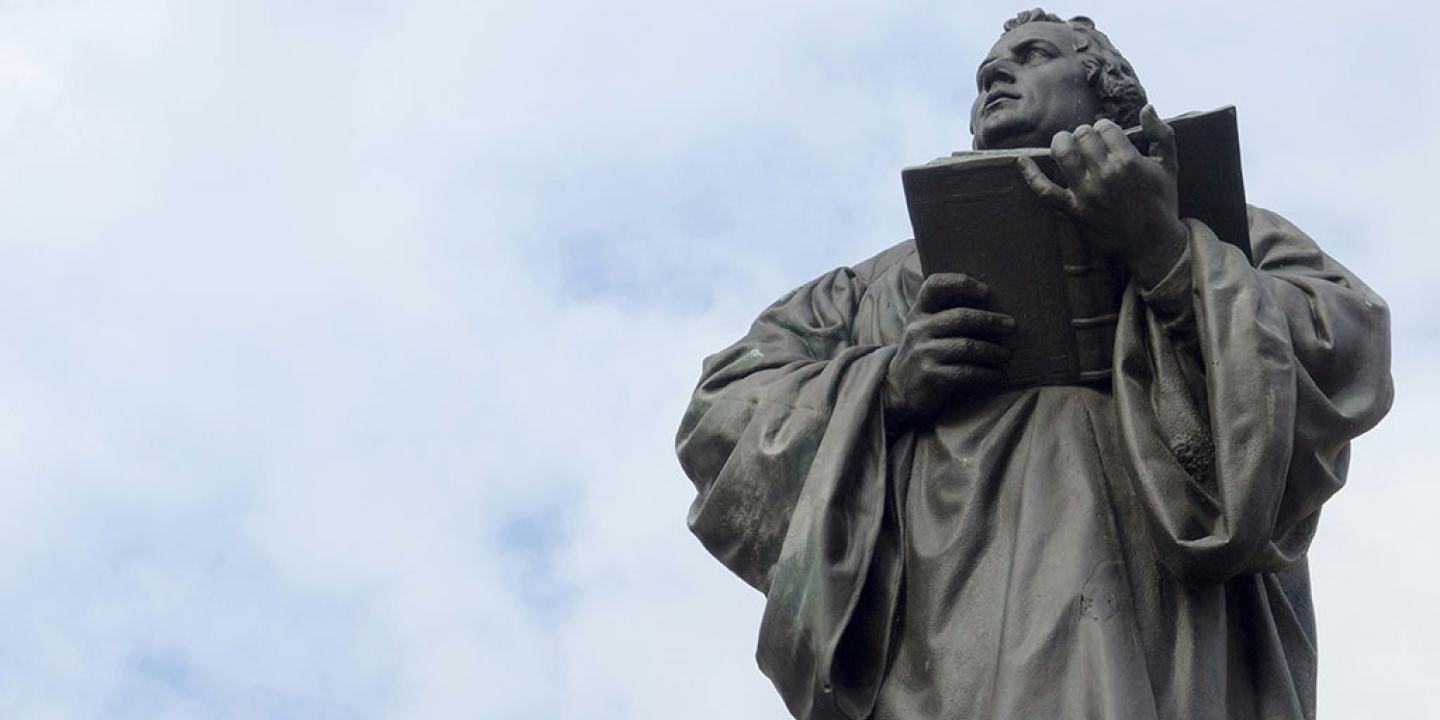 Looking up at a statue of Martin Luther holding an open bible.